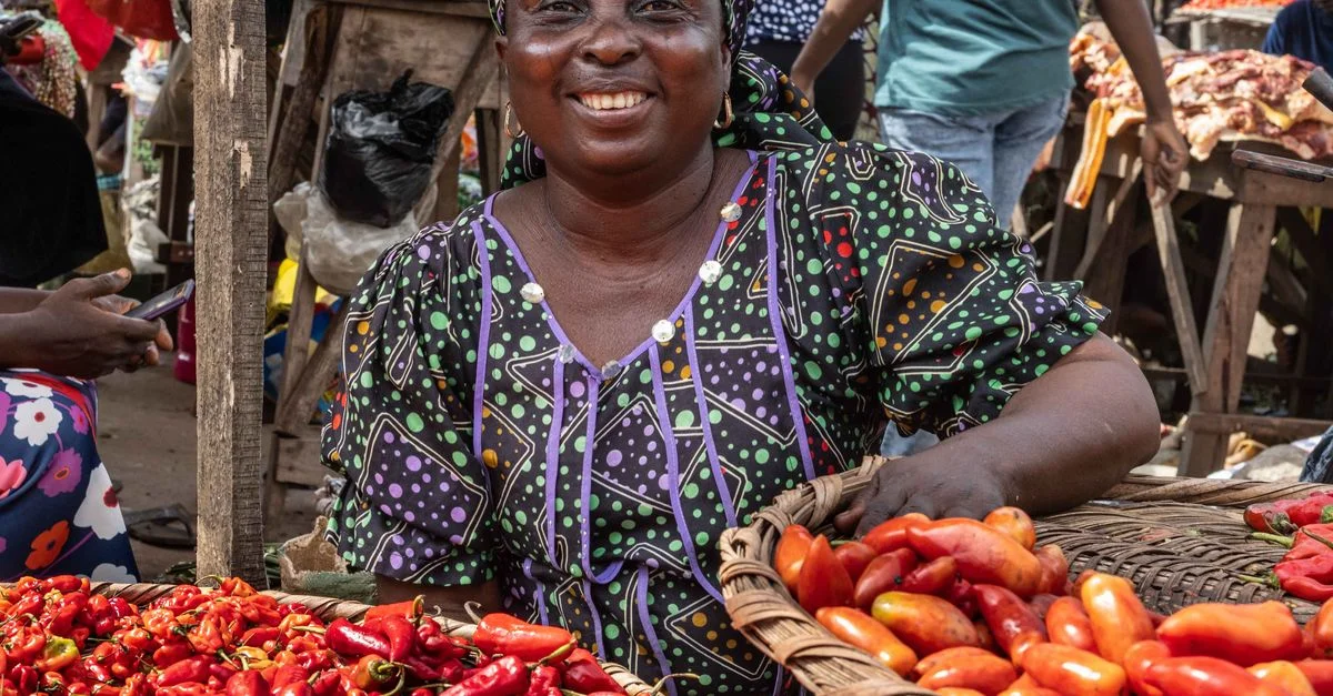 Un vendeur jovial vendant des poivrons frais dans un marché animé à Ogun, Nigéria.