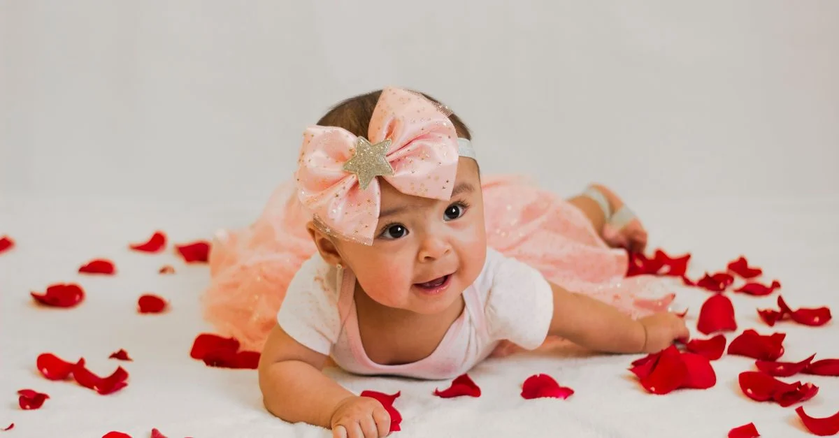 Jolie petite fille allongée sur des pétales de rose portant une robe avec un nœud rose. Parfait pour la photographie sur le thème des nourrissons.