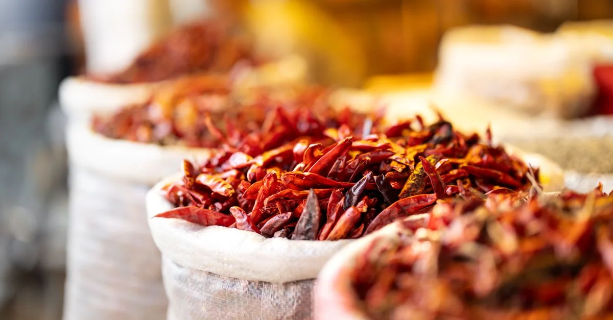 Gros plan de piments rouges vifs dans des sacs, capturés dans un décor de marché indien, mettant en valeur des épices vibrantes.