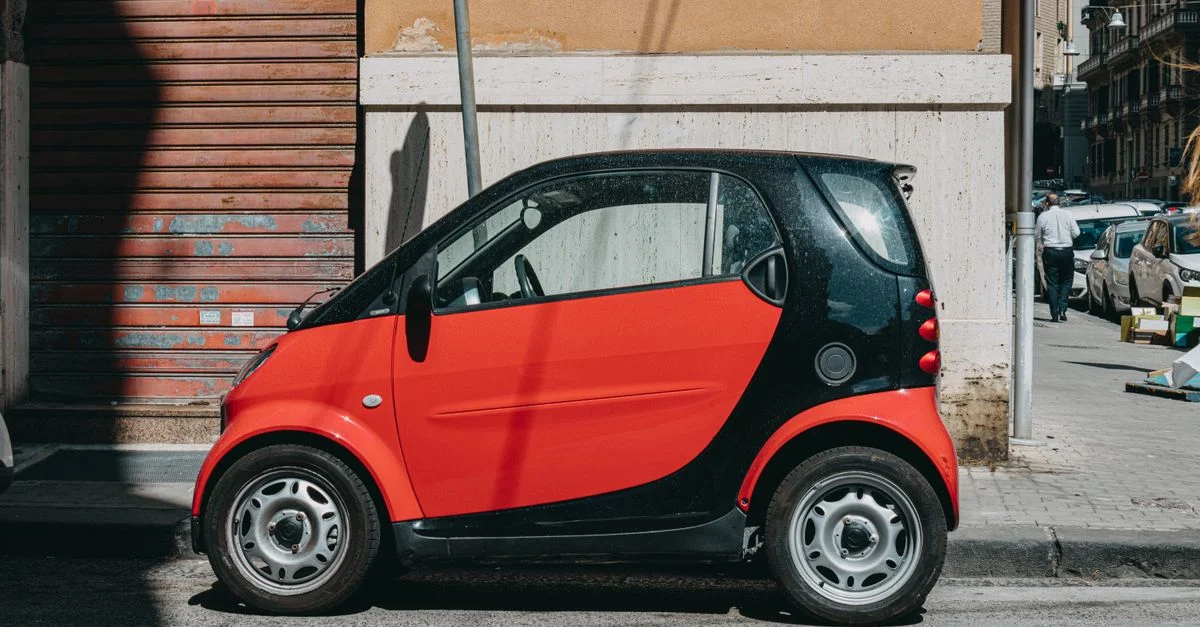 Vue latérale d'une voiture compacte rouge garée dans une rue à Naples, en Italie.