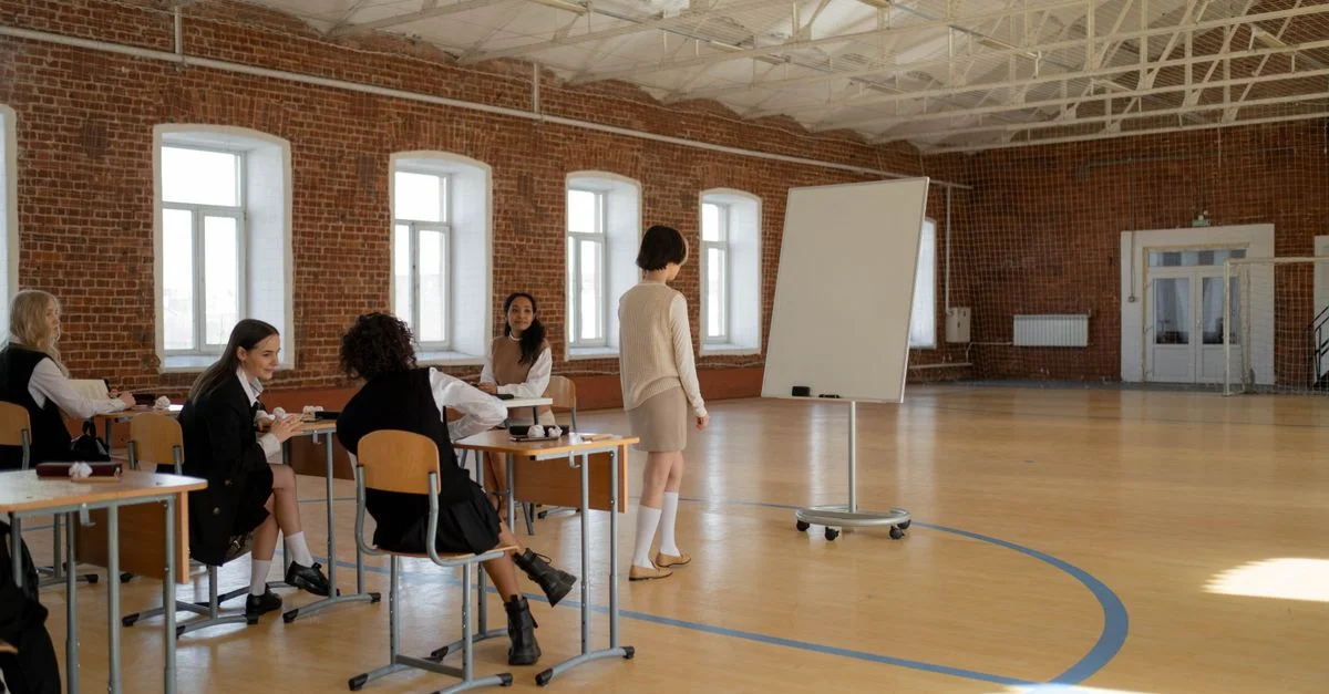 Des étudiants en uniformes scolaires engagés dans une leçon avec un enseignant dans une salle de classe spacieuse.
