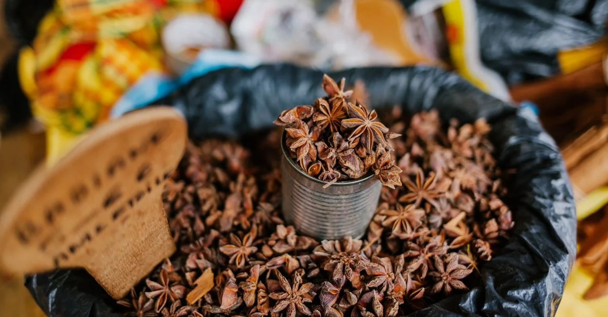 Badiane étoilée présentée dans une boîte sur un étal de marché, mettant en valeur son épice riche et aromatique utilisée en cuisine.