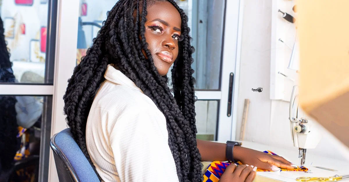 Une femme cousant avec un tissu vibrant dans un studio moderne, montrant concentration et créativité.