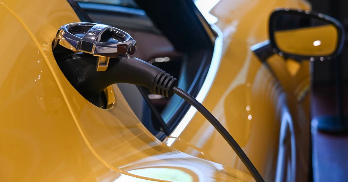 Gros plan sur un véhicule électrique jaune en charge à l'intérieur, via un câble branché.